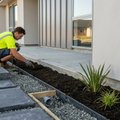 Newly laid paving and a freshly planted garden bed running alongside the concrete slab edge of a modern New Zealand home
