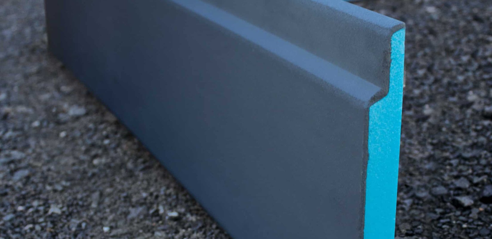 Exposed concrete slab perimeter of an Auckland house during a retrofit, with insulation boards being fitted along the slab edge before backfill