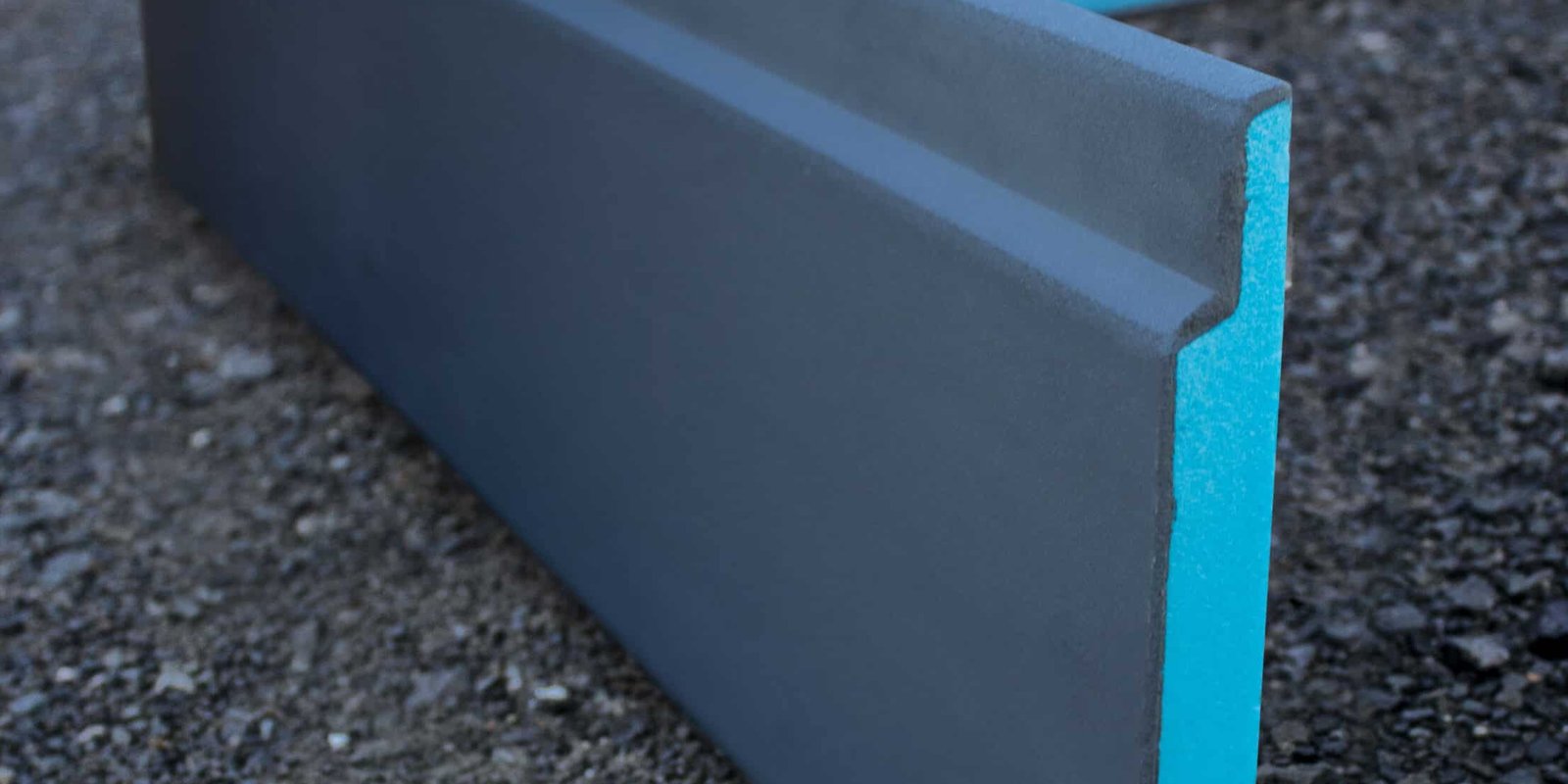 Exposed concrete slab perimeter of an Auckland house during a retrofit, with insulation boards being fitted along the slab edge before backfill